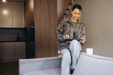 Woman working on tablet from home using tablet and drinking coffee