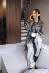 Woman sitting on sofa at home and using mobile phone