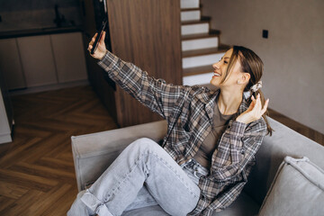Woman sitting on sofa at home and using mobile phone