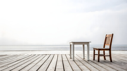 A wooden table and chairs rest on a scenic outdoor terrace overlooking the calm blue ocean and sunlit horizon at a relaxing summer beach resort