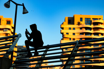 silhouette of a kid using a mobile phone in the city