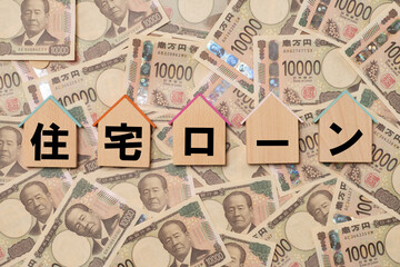 住宅ローンの文字と家形のプレートと敷き詰められた一万円札