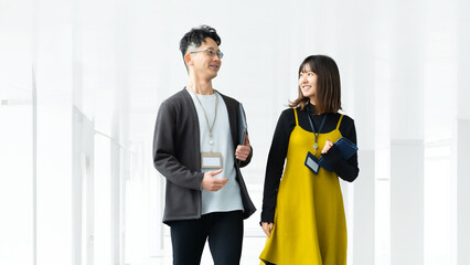 オフィスを歩きながら話す男女2人のビジネスマン