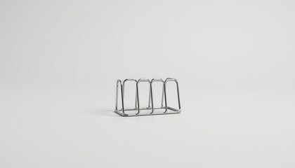 An object that resembles a set of three metal brackets, positioned upright in the center of the frame against a neutral grey background