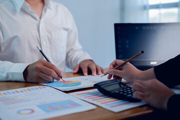 Business professionals reviewing financial charts with laptop and calculator on desk, teamwork concept for financial planning, data analysis, budgeting, consulting, strategy and decision making.