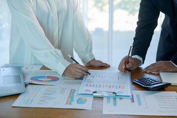 Business people analyzing financial charts and graphs on desk with calculator and laptop, concept of data analysis, financial planning, corporate strategy, teamwork, reporting, business performance.