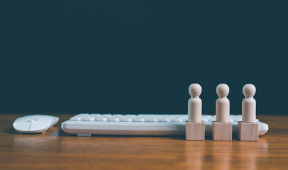 Wooden figures standing on blocks beside computer keyboard and mouse, representing office teamwork, digital workforce, remote work, business collaboration, human resources and modern workplace.
