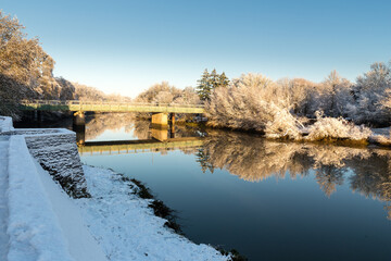 Obraz premium Pont au dessus d'une rivière après un épisode de neige, jolis reflets à la surface de l'eau. Pont de la Morinière, Rezé
