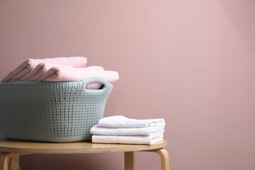 Laundry basket with towels on wooden table near beige wall indoors. Space for text