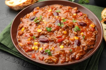 Delicious chili con carne served on black table, closeup