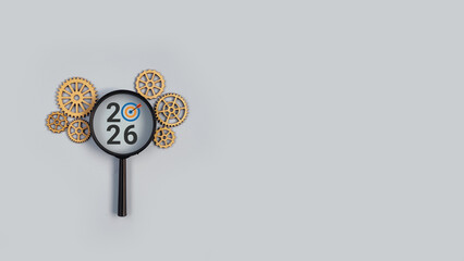 Gear elements arranged on left and right sides with a magnifying glass in the center displaying year 2026, where the zero is replaced with a target icon, symbolizing focus, strategy, planning, goals