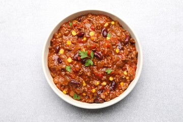 Delicious chili con carne in bowl on light gray table, top view