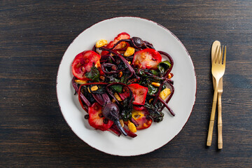 Fried beet stems with apples, raisins, peanuts, and garlic on a plate, closeup, top view. Cooking roasted beetroot with spices. Healthy food concept