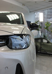 Front part of a new car in the foreground in a car showroom   
