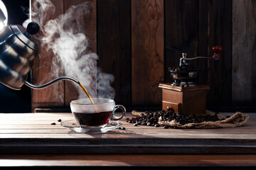Pour black coffee into a coffee cup There are roasted coffee beans on the table. with a black background and dark colors