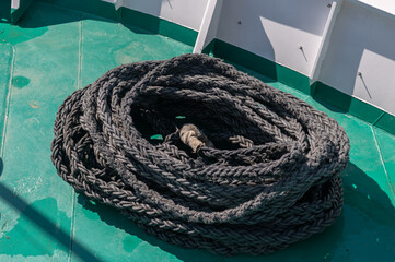 A black rope is rolled up on the ship's deck.