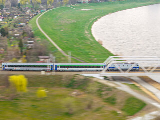 Pociąg pasażerski przejeżdżający przez most kolejowy nad rzeką Odrą w Opolu, ujęcie z góry ukazujące infrastrukturę transportową i nadrzeczne tereny zielone. © Henryk Niestrój