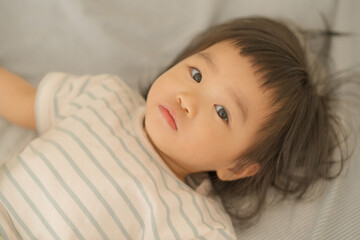 Peaceful Baby Lying on Bed with Soft Natural Light.