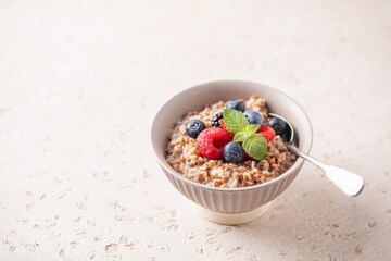 Milk sweet buckwheat porridge with berries in a bowl on the table. Healthy breakfast