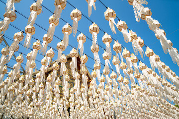 Traditional White Lanna Lanterns Hanging Against Blue Sky in Northern Thailand Temple