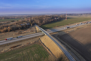 Węzeł komunikacyjny widziany z dużej wysokości. Skrzyżowanie lokalnej drogi z dwupasmową trasą szybkiego ruchu. Zdjęcie z drona.