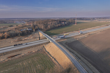 Węzeł komunikacyjny widziany z dużej wysokości. Skrzyżowanie lokalnej drogi z dwupasmową trasą szybkiego ruchu. Zdjęcie z drona.
