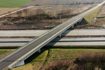 Węzeł komunikacyjny widziany z dużej wysokości. Skrzyżowanie lokalnej drogi z dwupasmową trasą szybkiego ruchu. Zdjęcie z drona.