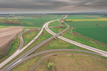 Węzeł komunikacyjny widziany z dużej wysokości. Skrzyżowanie dw&oacute;ch autostrad ze zjazdami, wjazdami w formie serpentyn. Zdjęcie z drona.