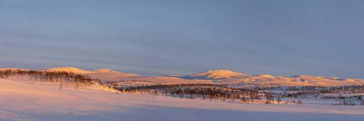 The evening sun shining over a snow-covered mountain range
