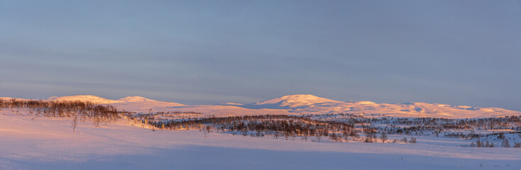 The evening sun shining over a snow-covered mountain range