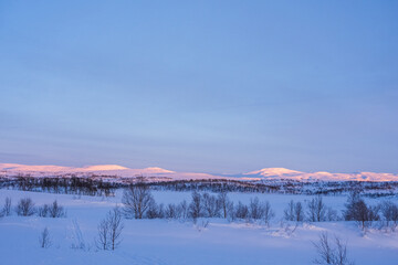 The evening sun shining over a snow-covered mountain range