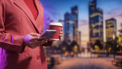 Business professional holding takeaway coffee and smartphone outdoors, modern city background, evening light urban lifestyle, mobile communication productivity work break,life balance.