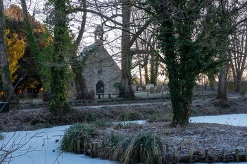 Obraz premium pond covered with snow with St Bartholomew's Church Botley Hampshire England in the background