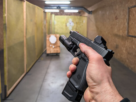 BALTIC STATES - JANUARY 6, 2026: Tactical training with a Glock 19 Gen5 pistol equipped with a red dot sight and weapon light during a shooting session at an indoor range.