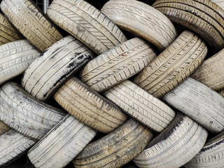 Obraz premium Used car tires arranged in a crisscross pattern create a textured geometric composition suitable for background images for Automotive Photography, Graphic Design, creative landscape projects.