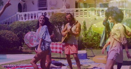 Playing man in striped tank and pink shorts strumming acoustic guitar at backyard pool with floats
