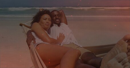 Naklejka premium Reclining couple leaning on low lounge chair on sand, wearing swimwear with ocean waves and horizon