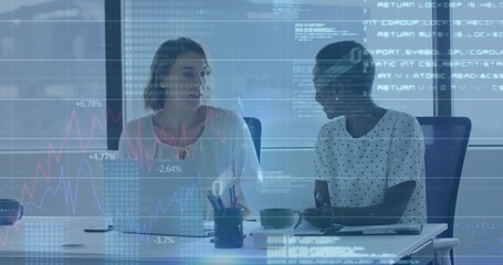 Discussing data overlay, two colleagues reviewing charts at meeting table with laptop, wearing tops