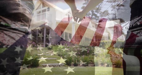 Holding hands couple in casual clothes in front yard of two-story house, with US flag overlay