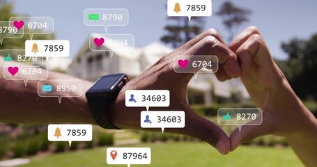Forming couple hands creating heart near camera in front yard, showing smartwatch and social alerts