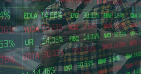 Crossing arms man in yellow-green plaid shirt checking phone on sidewalk, with watch, stock tickers