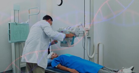Positioning tech leaning over senior woman in blue gown on table in X-ray room adjusting detector