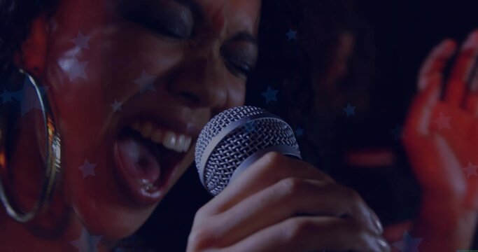Singing female singer gripping metal mic on club stage with hoop earring and star projections
