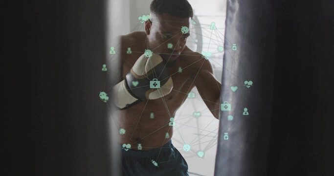 Punching shirtless boxer training in narrow gym with heavy bag, gloves and shorts, digital overlay - Powered by Adobe