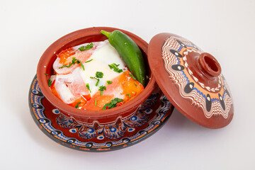 Traditional Bulgarian Sirene po Shopski, a delicious baked egg and cheese dish with tomatoes and peppers, served in an authentic decorated clay pot, gyuveche. 