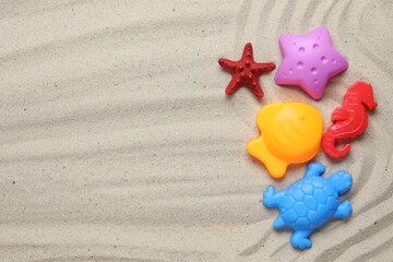 Bright children's beach toys and starfish on sand, flat lay. Space for text