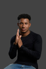 Confident young woman posing with her hands clasped in a studio.
