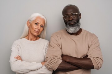 Mature Couple Posing Confidently in Casual Clothing Against Plain Background.