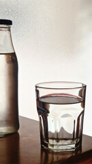 Glass bottle and drinking water on wooden table
