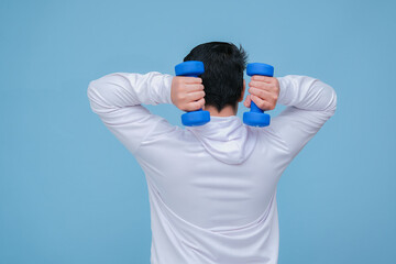 young asian man lifting dumbbells in both hands, seen from behind wearing a white t-shirt on turquoise blue background 